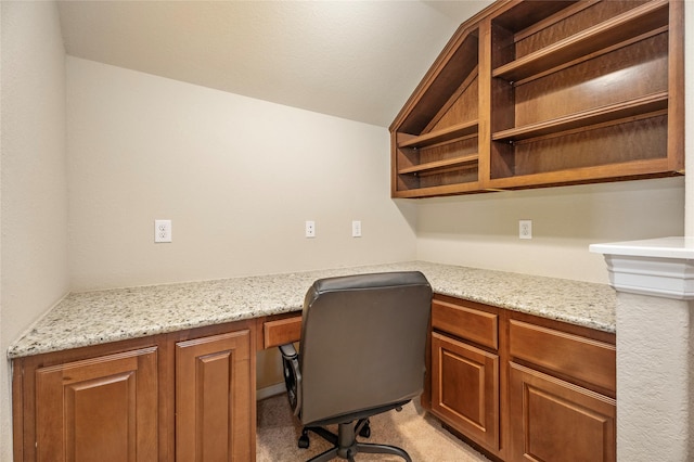 unfurnished office with light colored carpet, built in desk, and lofted ceiling