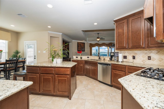 kitchen featuring light stone countertops, ceiling fan, a center island, sink, and stainless steel dishwasher