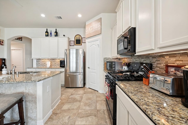 kitchen with white cabinetry, sink, stainless steel appliances, light stone counters, and decorative backsplash