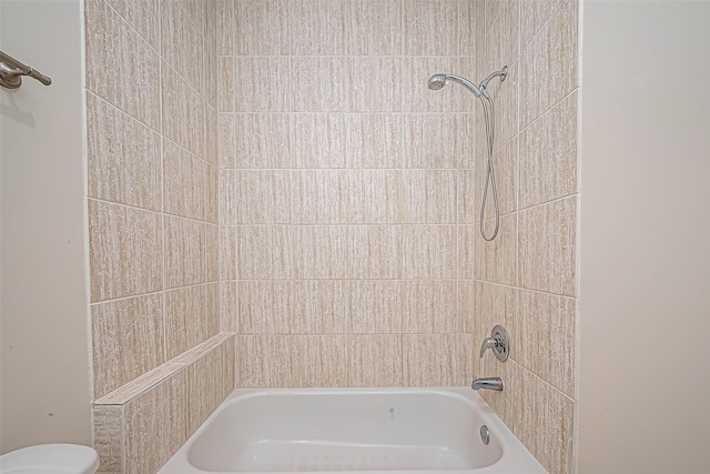 bathroom with tiled shower / bath combo and toilet