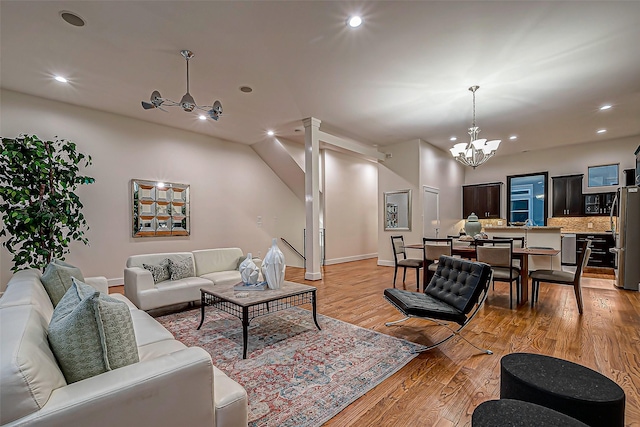 living room featuring ceiling fan with notable chandelier and light hardwood / wood-style flooring