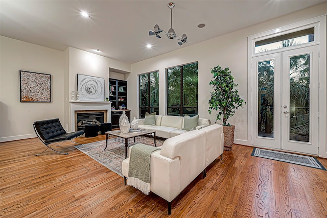 living room featuring a healthy amount of sunlight, french doors, hardwood / wood-style floors, and a notable chandelier