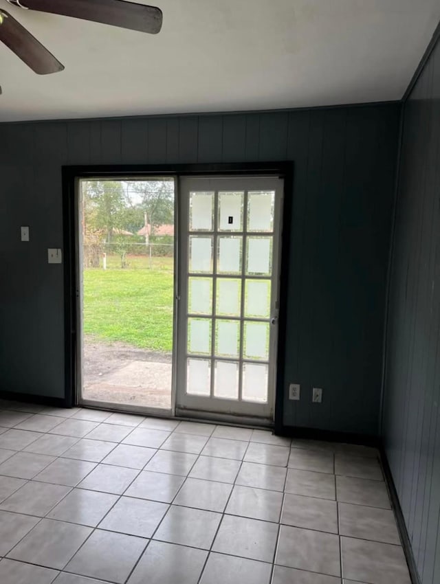 entryway with light tile patterned floors, ceiling fan, and wooden walls