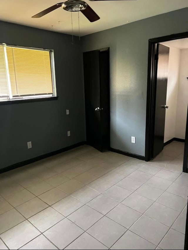 empty room with ceiling fan and light tile patterned floors