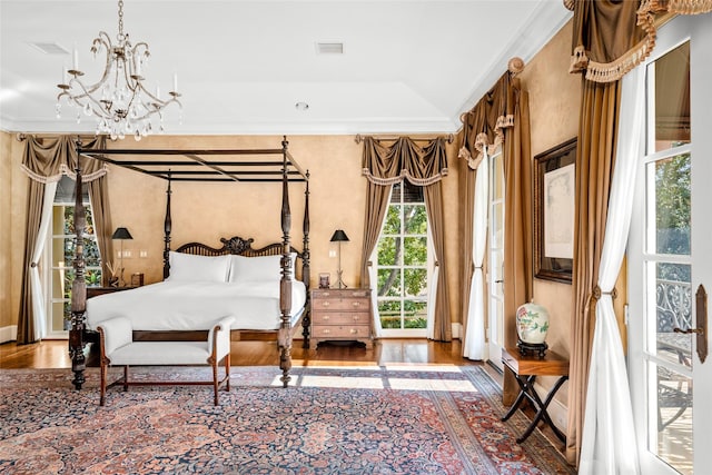 bedroom with hardwood / wood-style flooring, ornamental molding, and an inviting chandelier