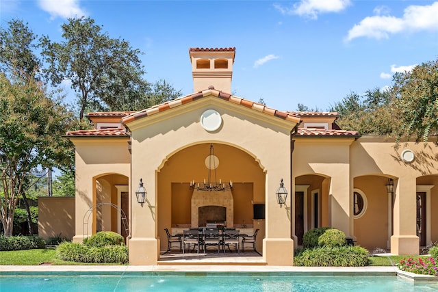 rear view of house featuring a patio and an outdoor fireplace