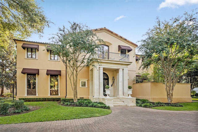 mediterranean / spanish-style house with a balcony and a front lawn