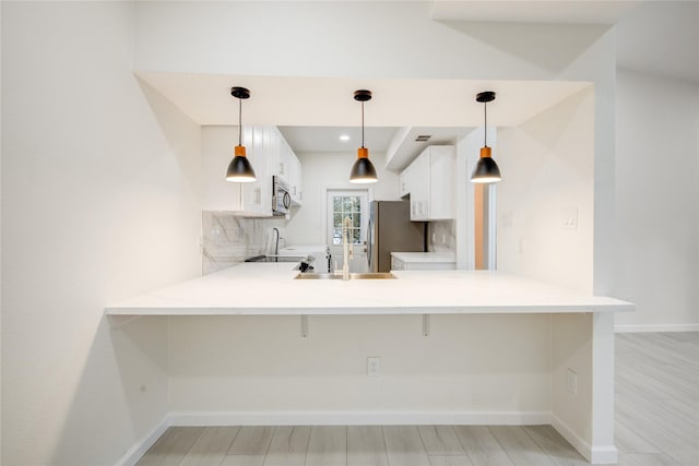 kitchen with kitchen peninsula, stainless steel appliances, white cabinetry, and hanging light fixtures