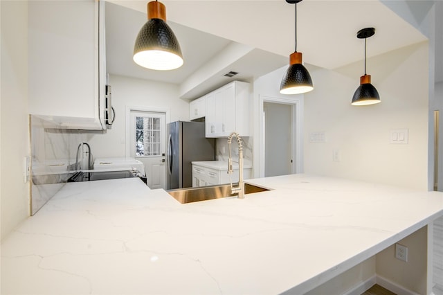 kitchen with pendant lighting, sink, stainless steel fridge, white cabinetry, and kitchen peninsula