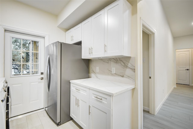 kitchen with decorative backsplash, stove, light stone counters, stainless steel fridge with ice dispenser, and white cabinetry