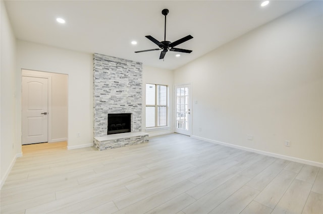 unfurnished living room featuring ceiling fan, a stone fireplace, light wood-type flooring, and lofted ceiling