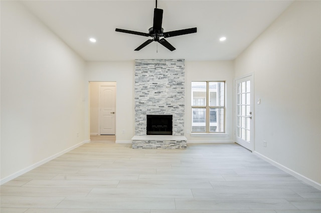 unfurnished living room featuring a stone fireplace, ceiling fan, and light hardwood / wood-style floors