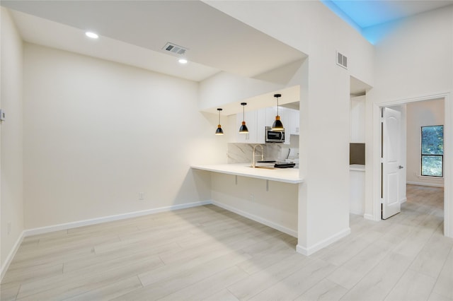 bar featuring pendant lighting, light wood-type flooring, and backsplash