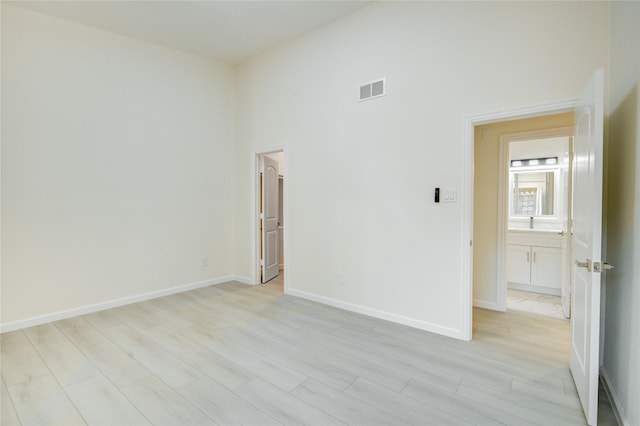 unfurnished room with a high ceiling and light wood-type flooring