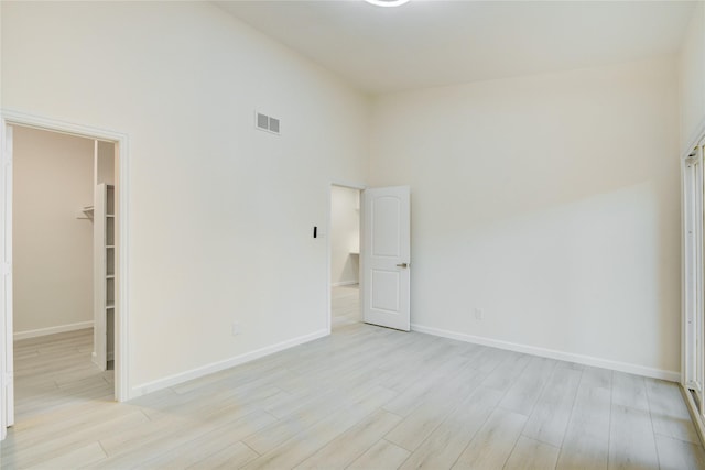 unfurnished room with light hardwood / wood-style floors and a high ceiling