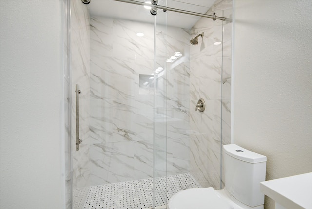 bathroom with a shower with shower door and toilet