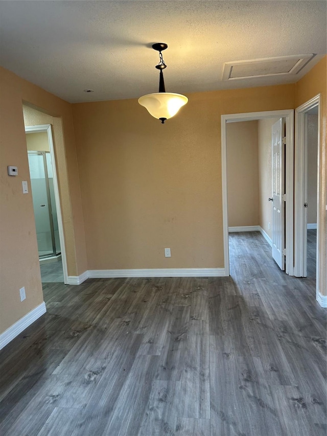 unfurnished dining area with a textured ceiling and dark wood-type flooring