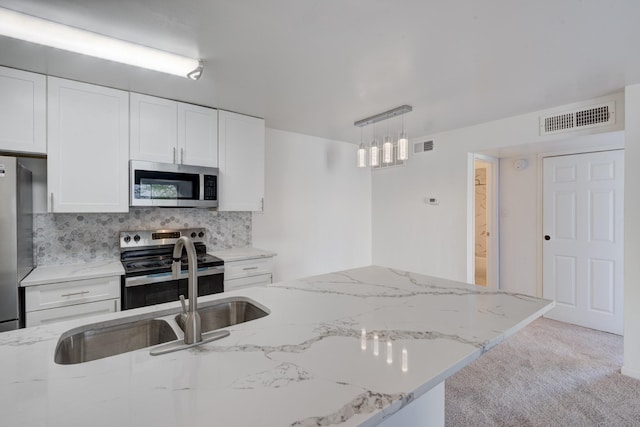 kitchen with decorative backsplash, appliances with stainless steel finishes, light colored carpet, pendant lighting, and white cabinetry