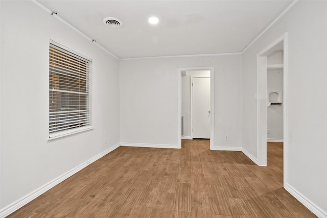 spare room featuring ornamental molding and light hardwood / wood-style flooring