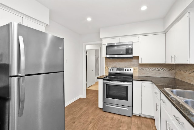 kitchen with decorative backsplash, light wood-type flooring, stainless steel appliances, sink, and white cabinetry