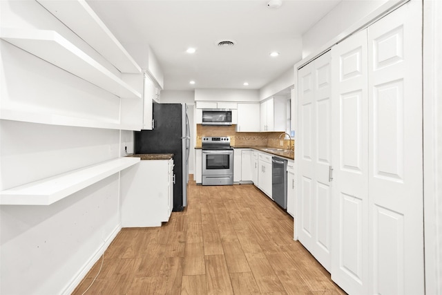 kitchen with white cabinets, sink, decorative backsplash, light hardwood / wood-style floors, and stainless steel appliances