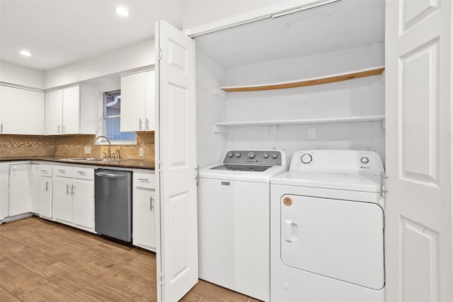 clothes washing area featuring sink, washer and clothes dryer, and light hardwood / wood-style flooring