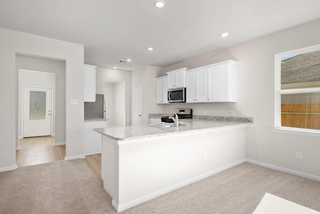 kitchen featuring white cabinetry, light colored carpet, kitchen peninsula, and stainless steel appliances