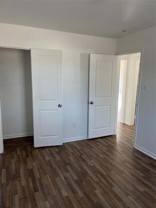 unfurnished bedroom with dark wood-type flooring and a closet