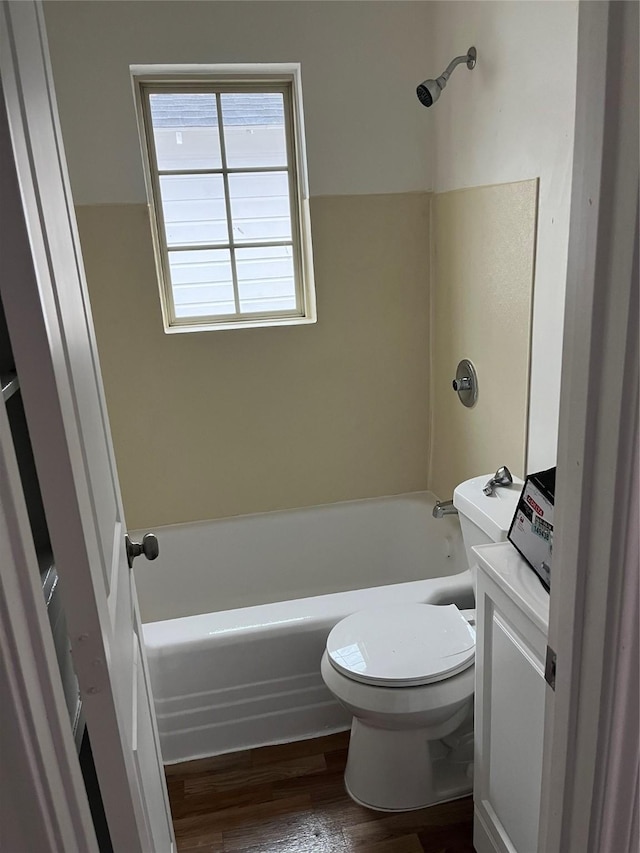 bathroom with bathing tub / shower combination, wood-type flooring, and toilet