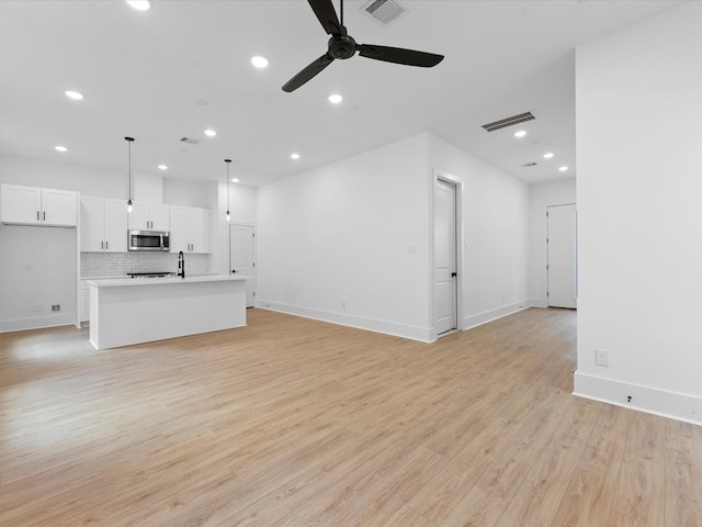 unfurnished living room with ceiling fan, light wood-type flooring, and sink