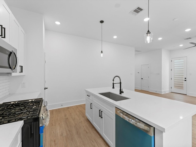 kitchen with sink, hanging light fixtures, an island with sink, white cabinets, and appliances with stainless steel finishes