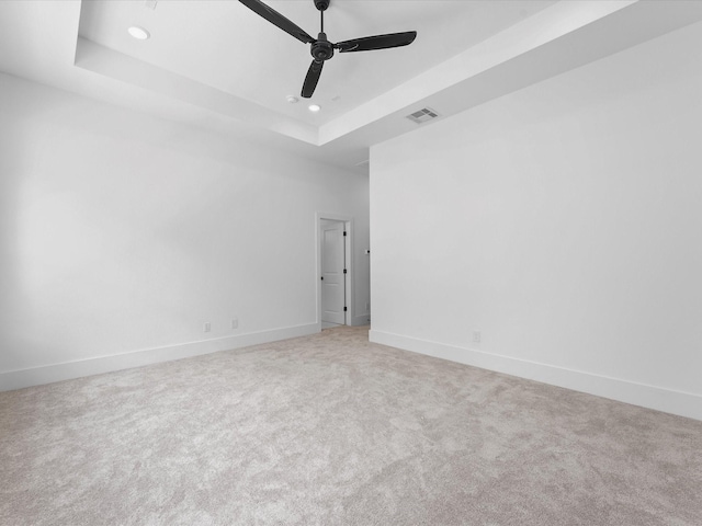 carpeted spare room with a tray ceiling and ceiling fan