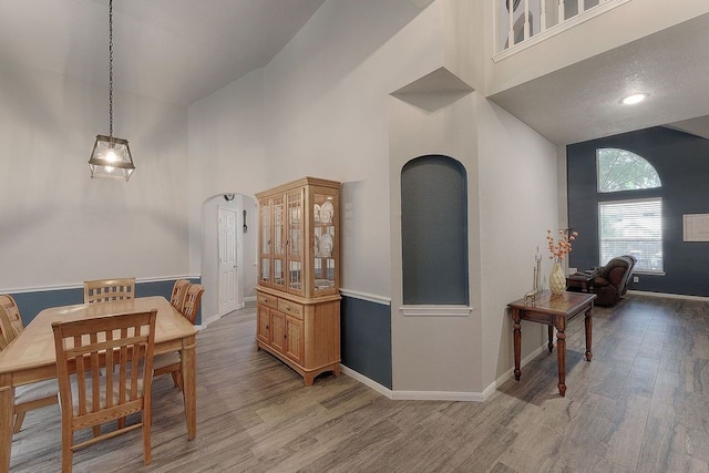 dining area with light wood-type flooring and high vaulted ceiling