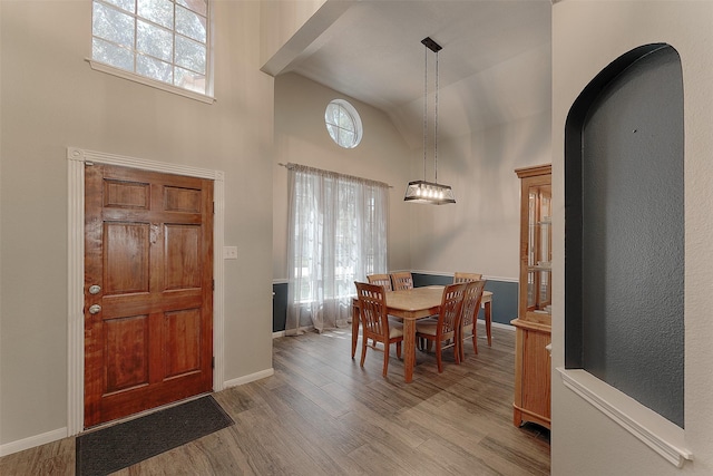 dining area featuring high vaulted ceiling and light hardwood / wood-style floors