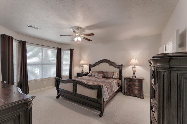 bedroom featuring ceiling fan, light colored carpet, and a textured ceiling