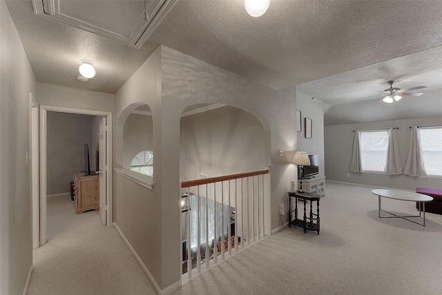 hall with light colored carpet and a textured ceiling