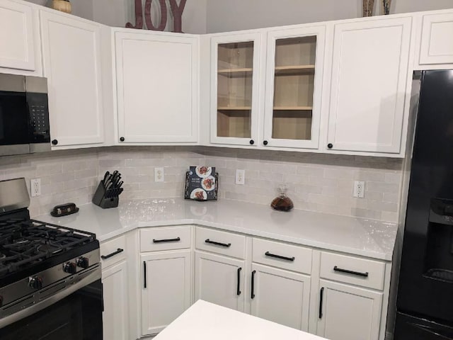 kitchen featuring white cabinets, appliances with stainless steel finishes, and decorative backsplash