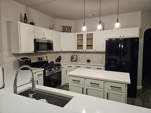 kitchen with appliances with stainless steel finishes, white cabinetry, sink, decorative light fixtures, and backsplash