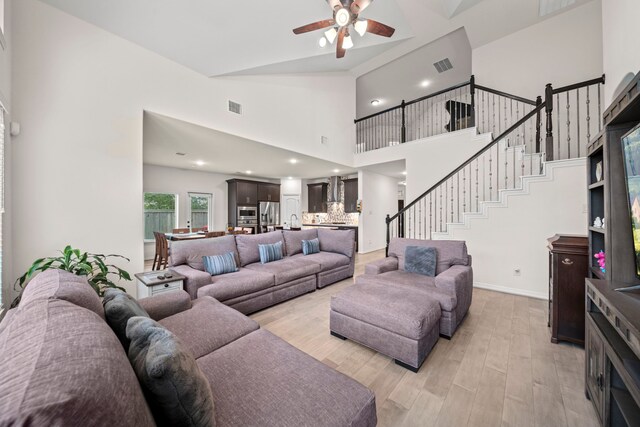 living room with high vaulted ceiling, light hardwood / wood-style flooring, and ceiling fan