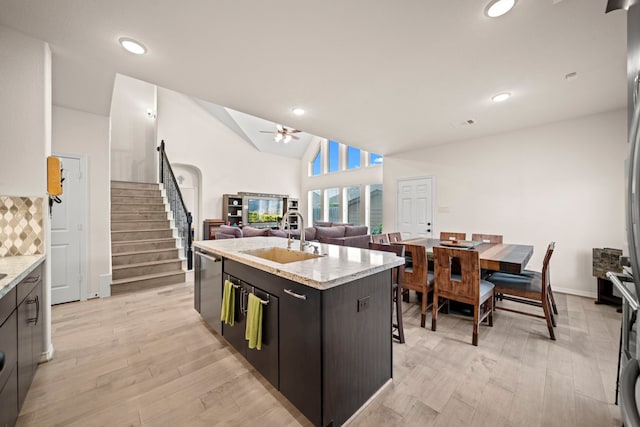 kitchen featuring ceiling fan, dishwasher, sink, an island with sink, and dark brown cabinets