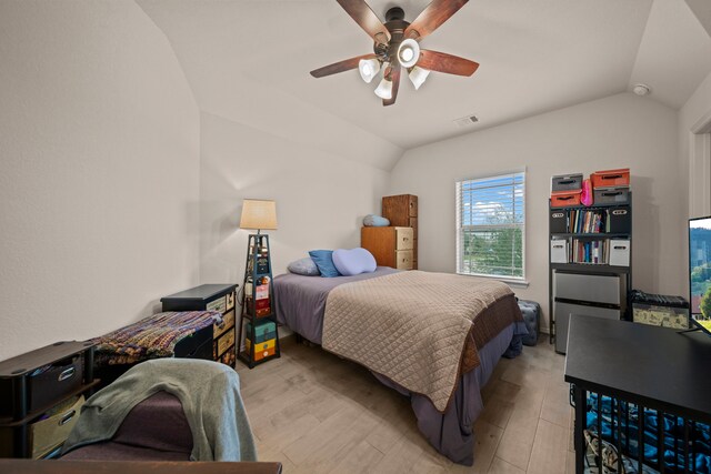 bedroom with ceiling fan, vaulted ceiling, and light hardwood / wood-style flooring