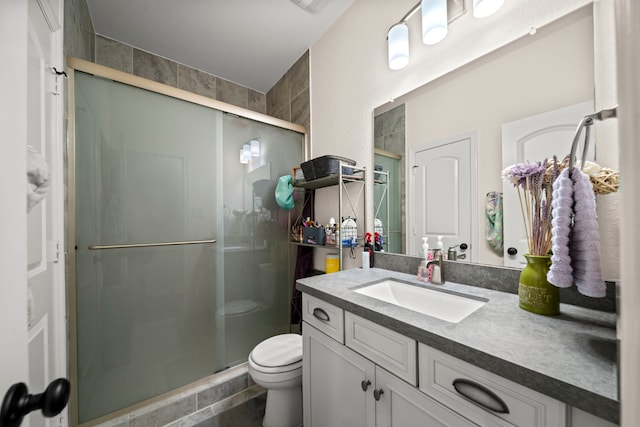 bathroom with vanity, toilet, and a shower with door