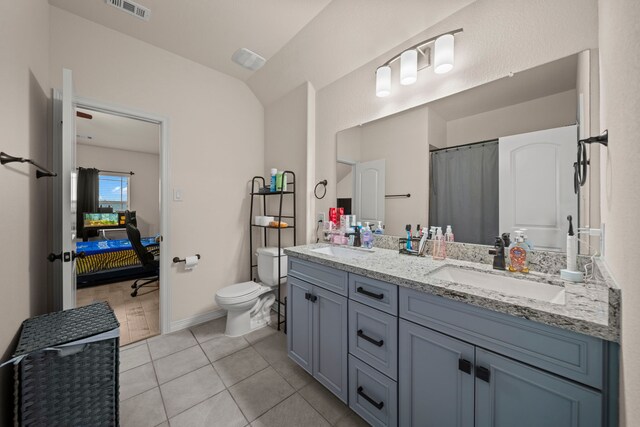 bathroom featuring toilet, vanity, tile patterned floors, and vaulted ceiling