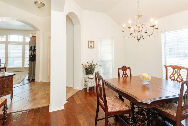 dining room with dark hardwood / wood-style flooring, lofted ceiling, and a notable chandelier