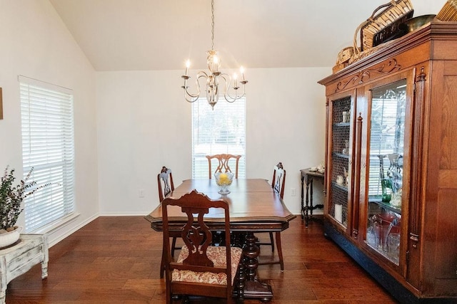 dining space with dark hardwood / wood-style flooring, lofted ceiling, and an inviting chandelier