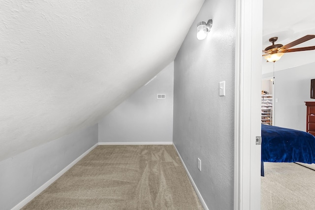 walk in closet featuring ceiling fan, light colored carpet, and vaulted ceiling