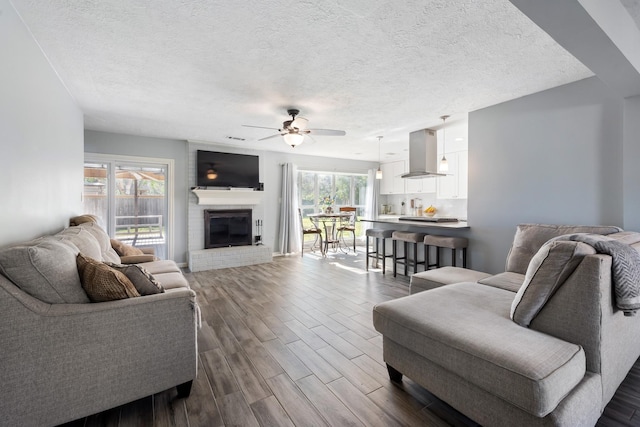 living room with a fireplace, a wealth of natural light, a textured ceiling, and ceiling fan