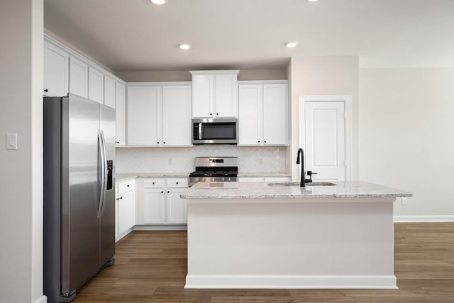 kitchen with light stone countertops, sink, an island with sink, and appliances with stainless steel finishes