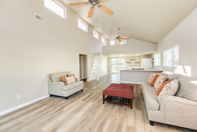 living room with light wood-type flooring, a high ceiling, and a wealth of natural light