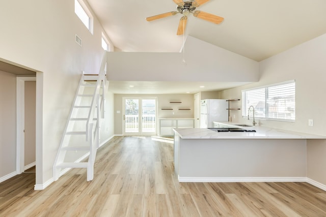 kitchen featuring sink, high vaulted ceiling, white refrigerator, kitchen peninsula, and light wood-type flooring